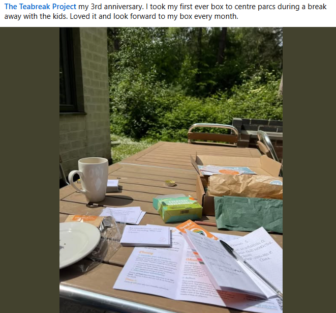 Community share: a Teabreak box opened on a holiday decking table with a mug, papers and supplies.