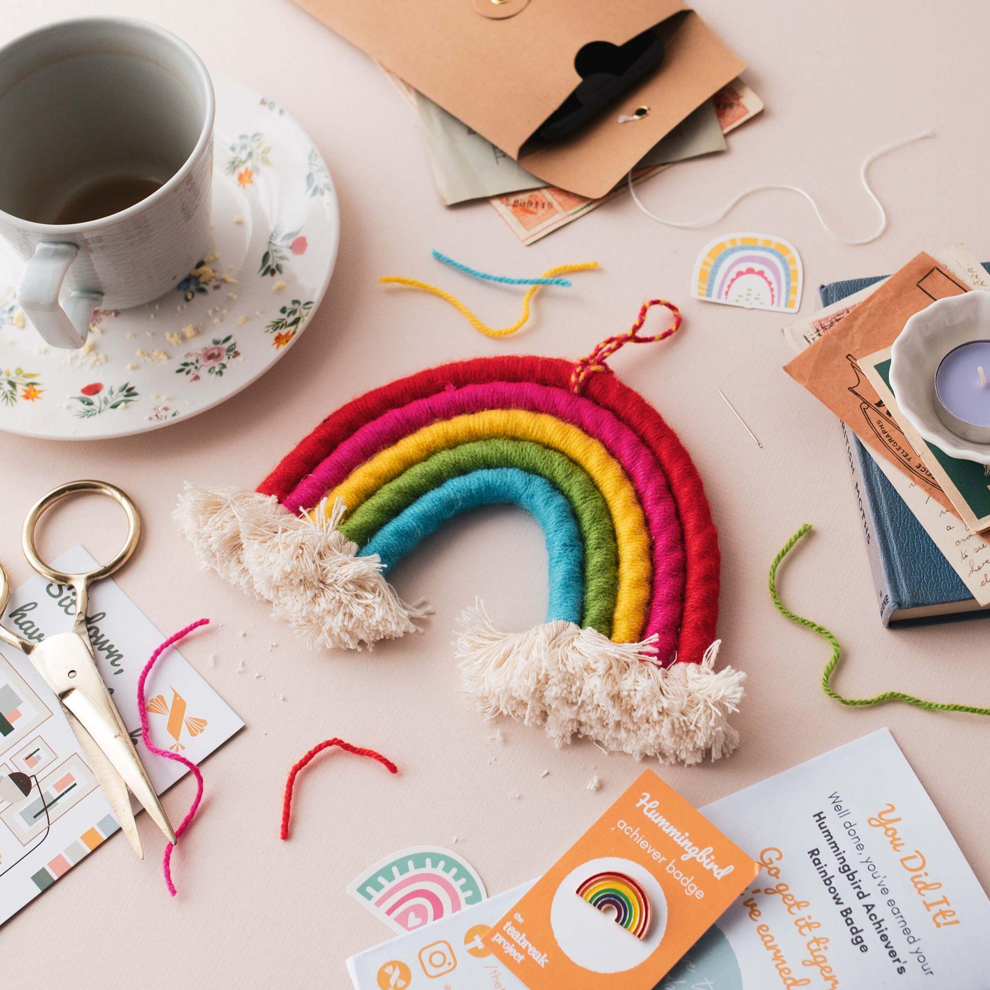 A cup of tea and a colourful handmade project arranged beside a gift envelope
