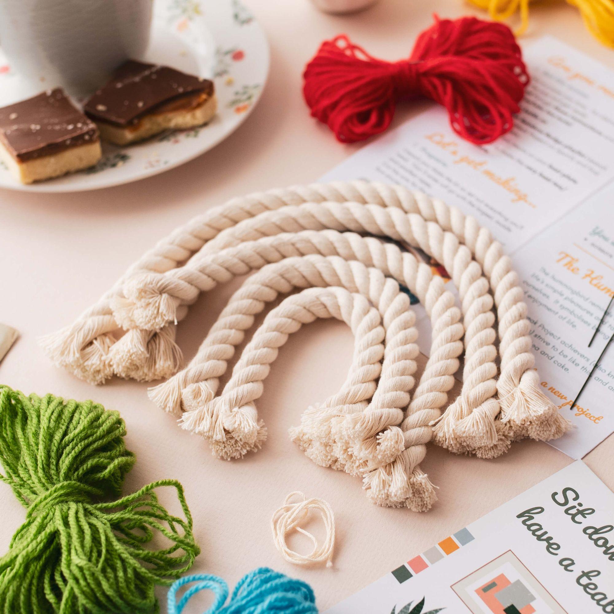 A partly finished rope craft project on a table with colourful yarn, cake and a Teabreak instruction card.