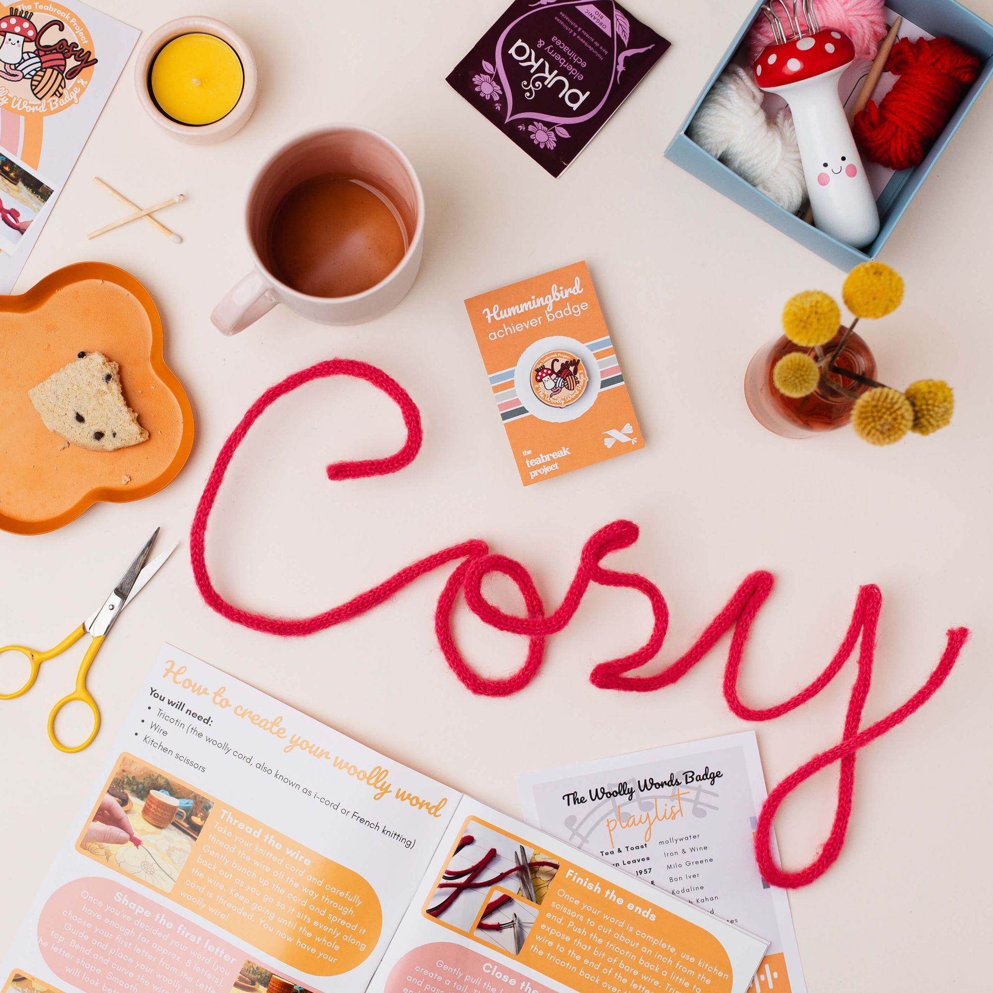 A Teabreak spread on a table with tea, cake, a tealight and the month's creative project