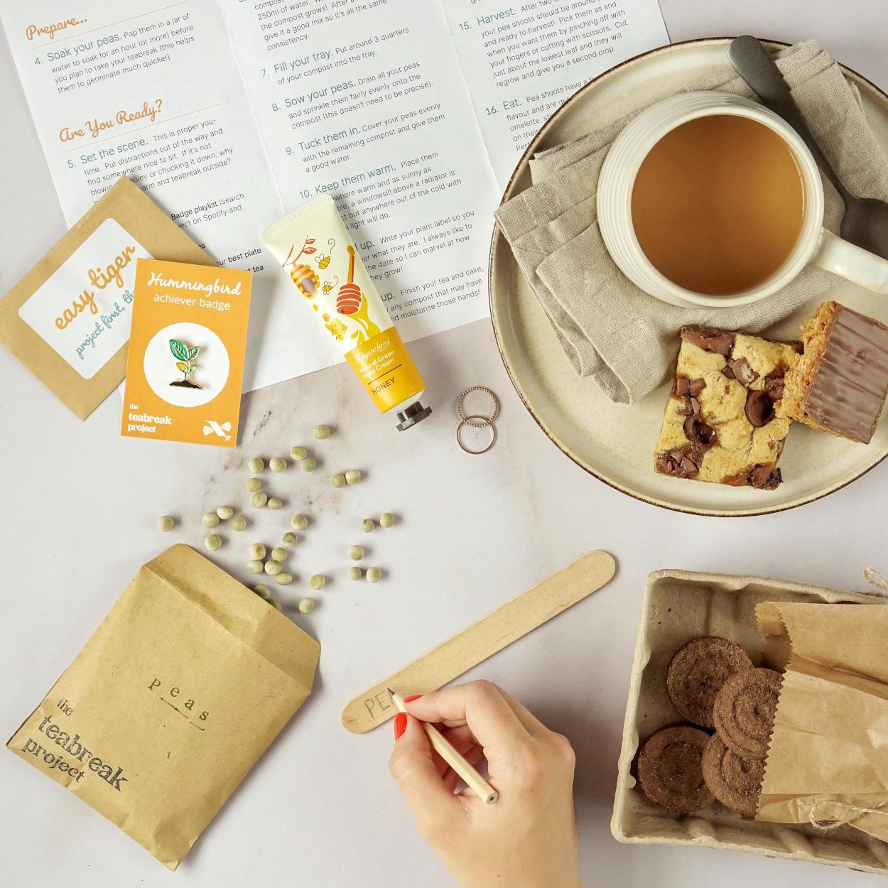 An open Teabreak box containing a creative project, tea, treats, tealights and Hummingbird extras